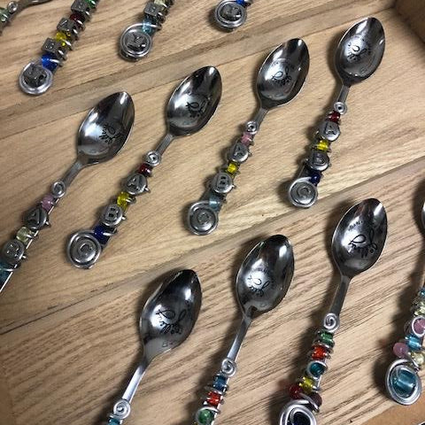 Decorative spoons with colorful beads on a wooden surface