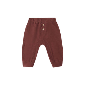 Burgundy baby pants with button details on a white background