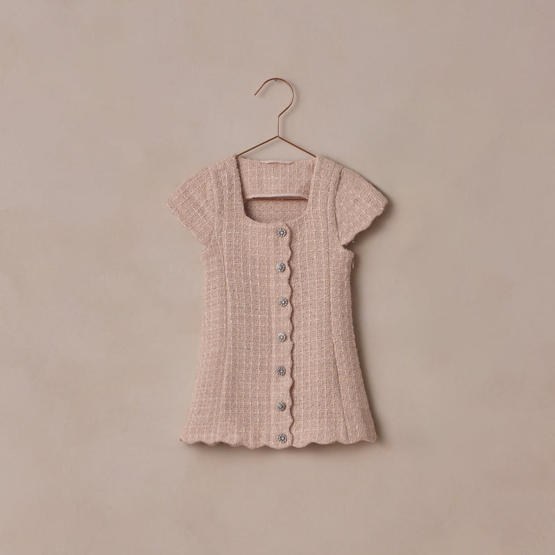 Pink textured dress on a hanger against a beige background