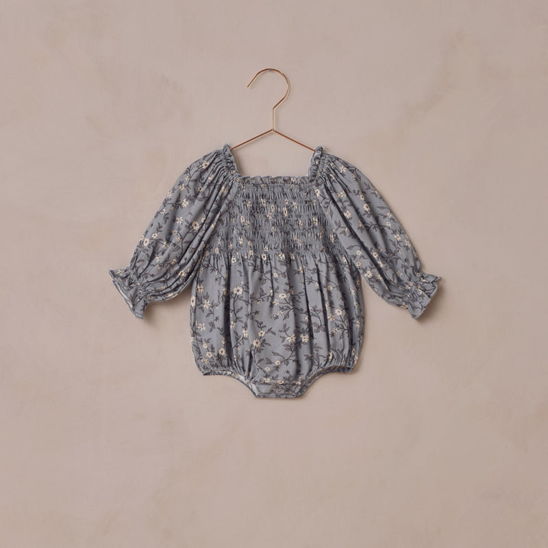 Baby romper with floral pattern on a beige background