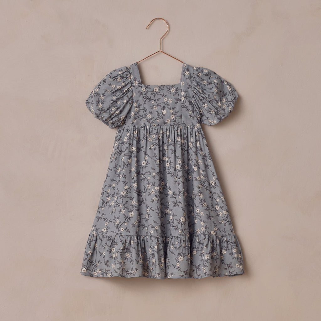 Floral dress on a hanger against a beige background