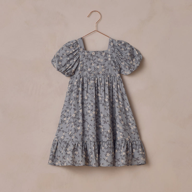Floral dress on a hanger against a beige background