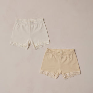 Two pairs of lace-trimmed shorts on a beige background