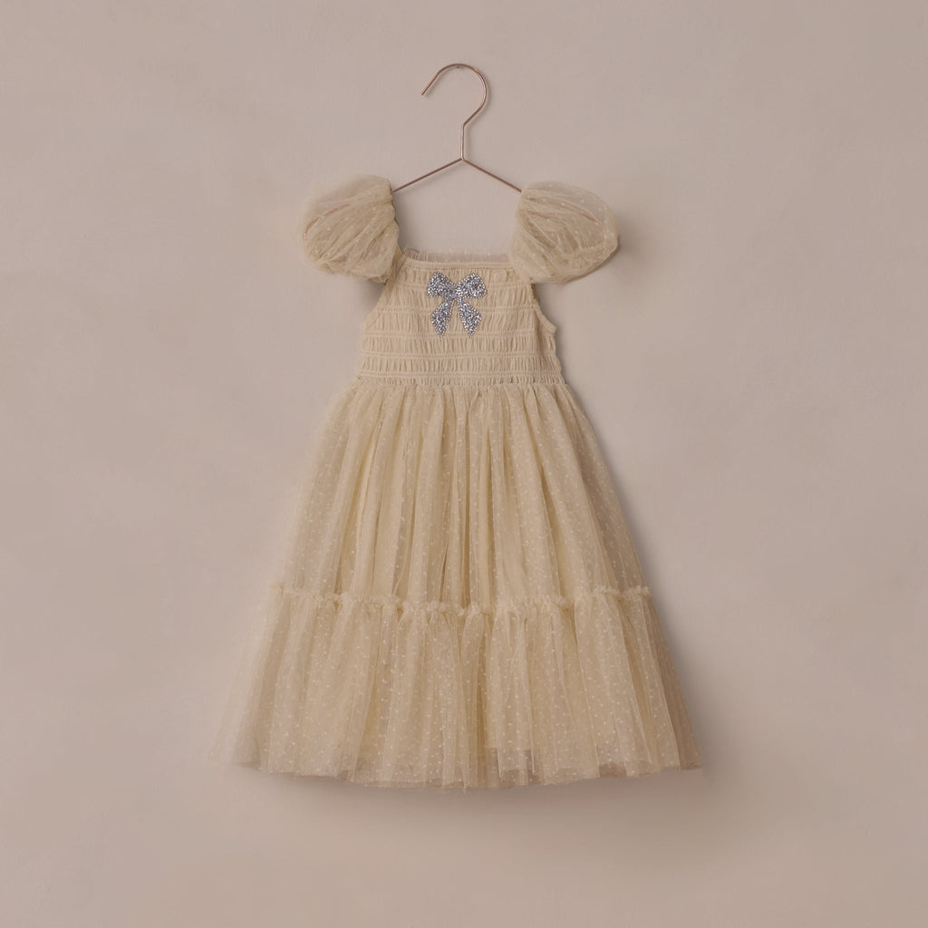 Champagne dress with sparkly bow embroidery on a beige background