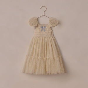 Champagne dress with sparkly bow embroidery on a beige background