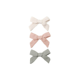 Three fabric bows in beige, pink, and fern green on a white background